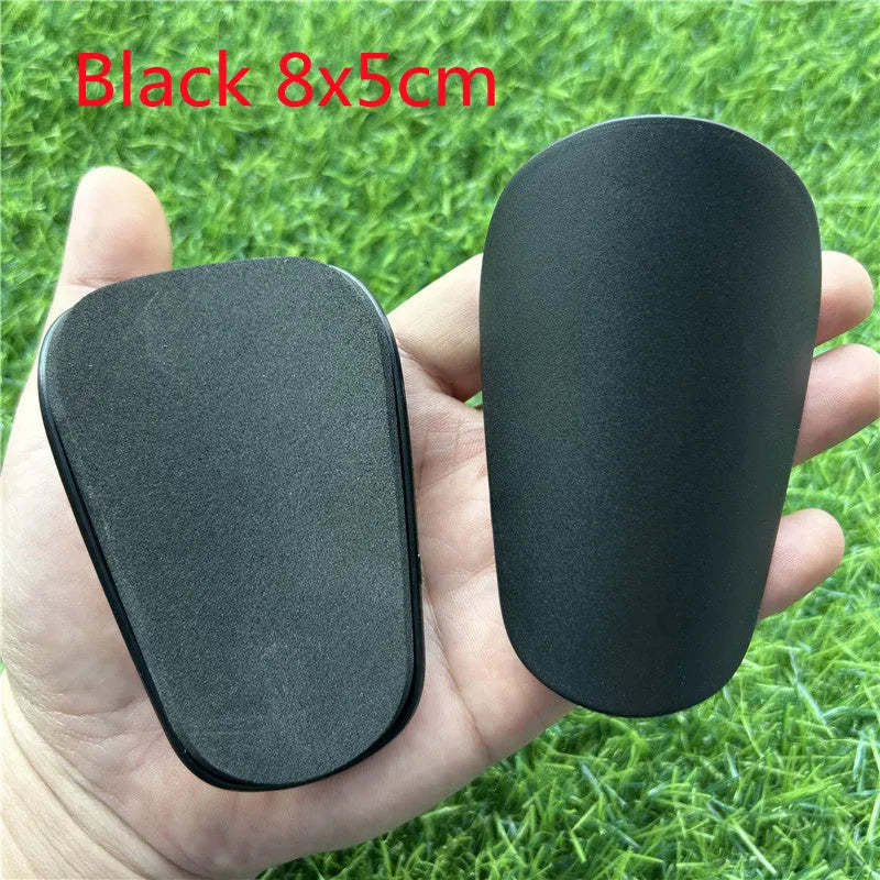 Extra small black and white plastic football shin guards for junior players.