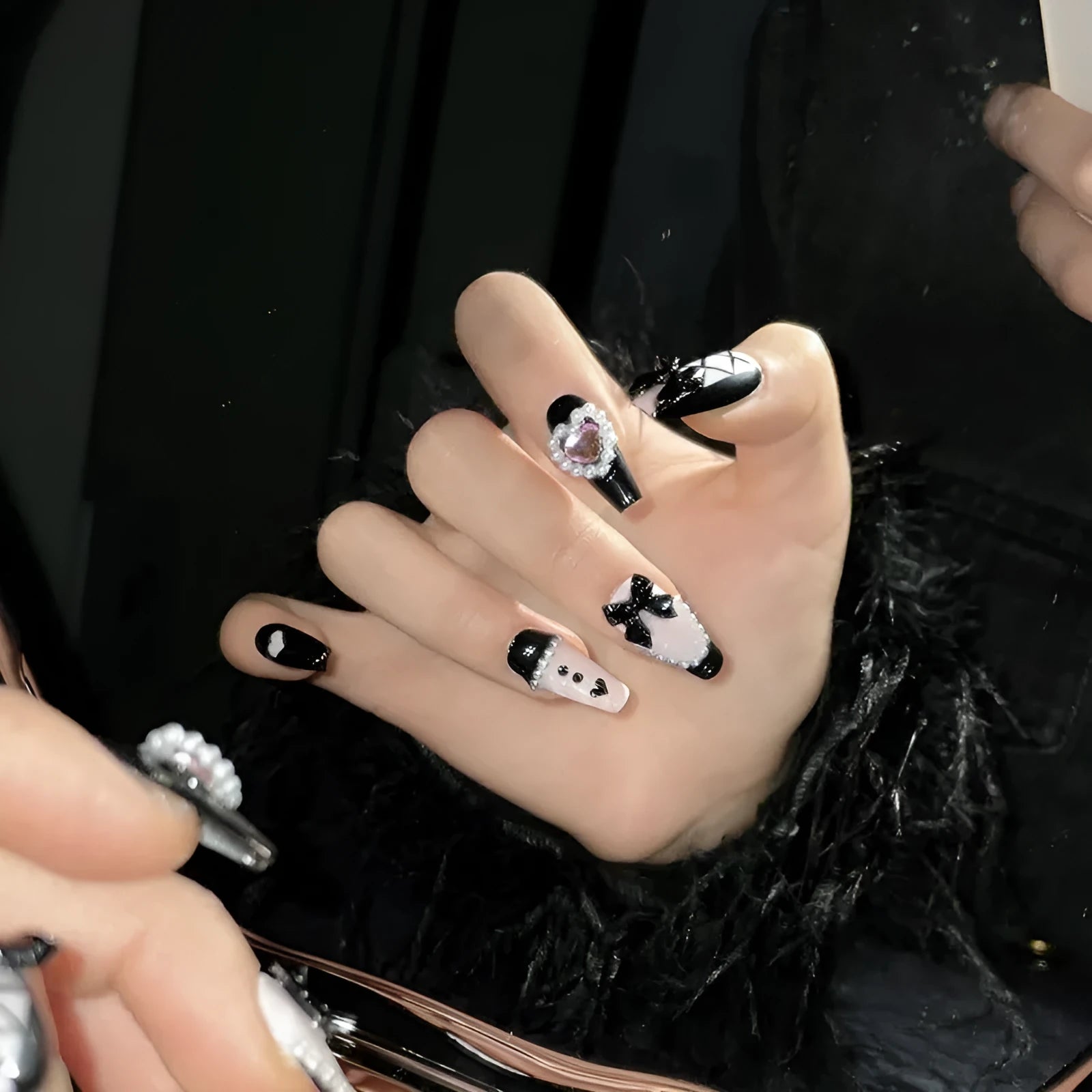 Detachable artificial nails with hand-painted black and pink heart design and cat's eye finish in four sizes