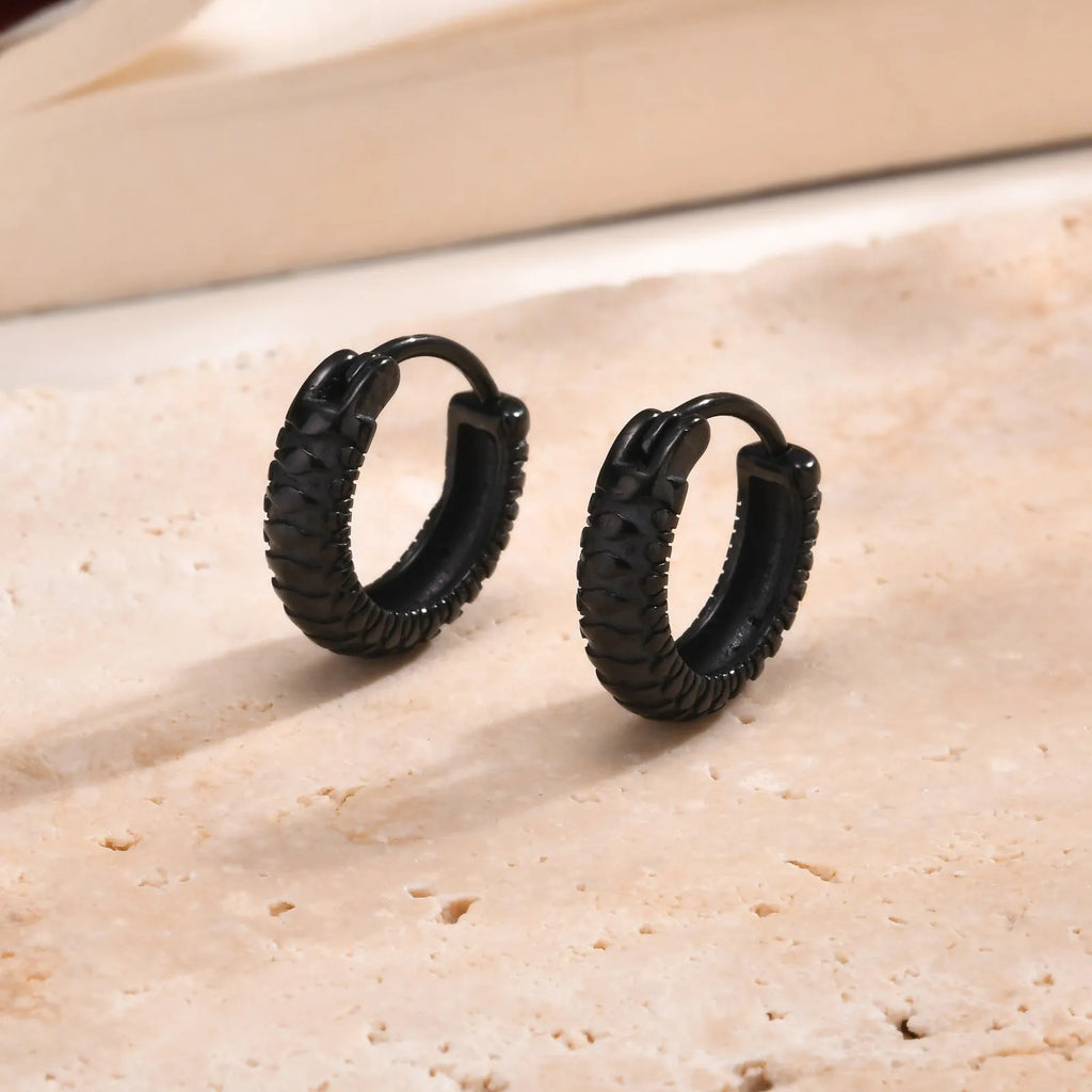 Close-up of a black stainless steel earring with a detailed snake pattern and hook fastening.