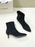 Black women's pointed toe Martin ankle boots with a high stiletto heel on a model.