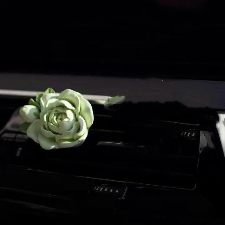 Solid jasmine car perfume diffuser clipped on a car air vent in off white or fresh green.