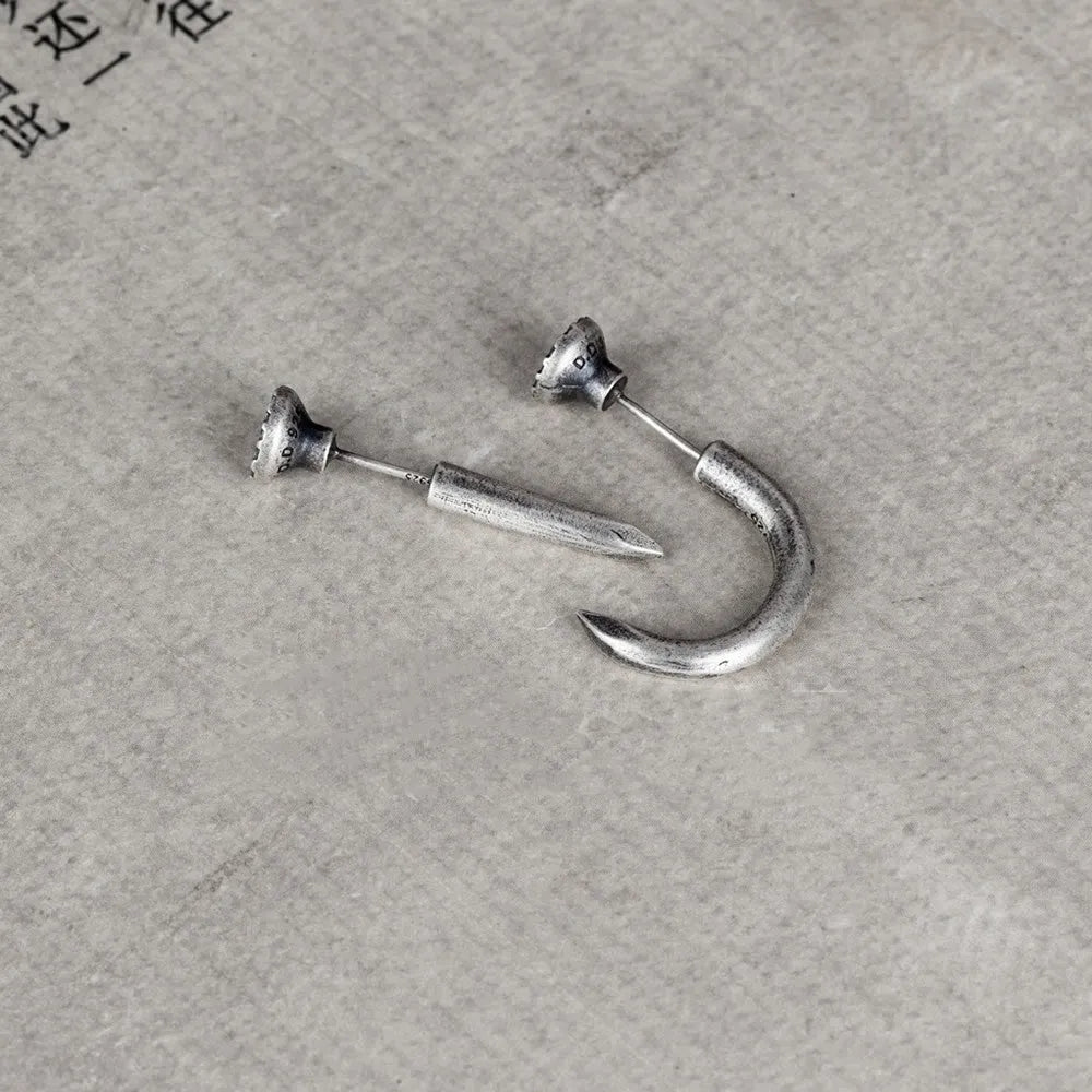 Close-up of a sterling silver punk stud earring with a retro nail design on an ear.