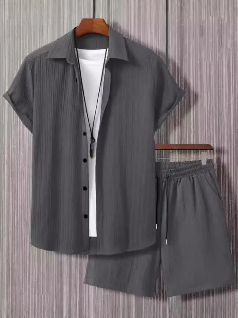 Man wearing a beige jacquard short sleeve suit jacket and matching shorts on a plain background.