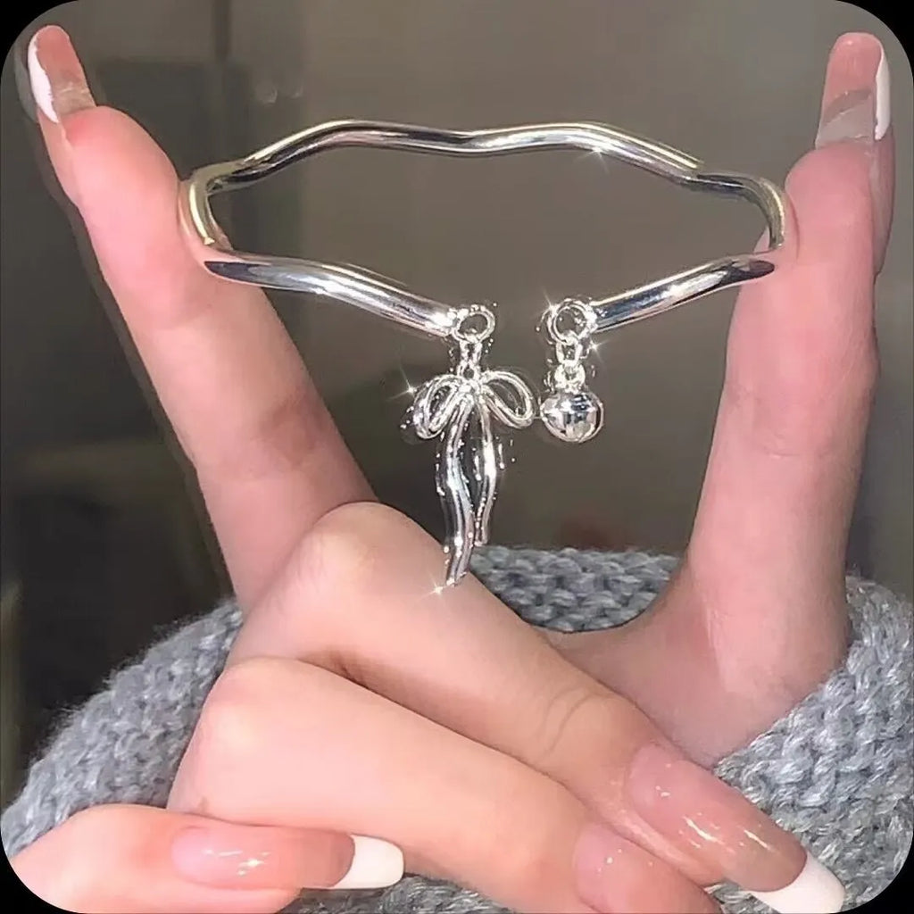 Silver bow adjustable bracelet with bell opening clasp on wrist