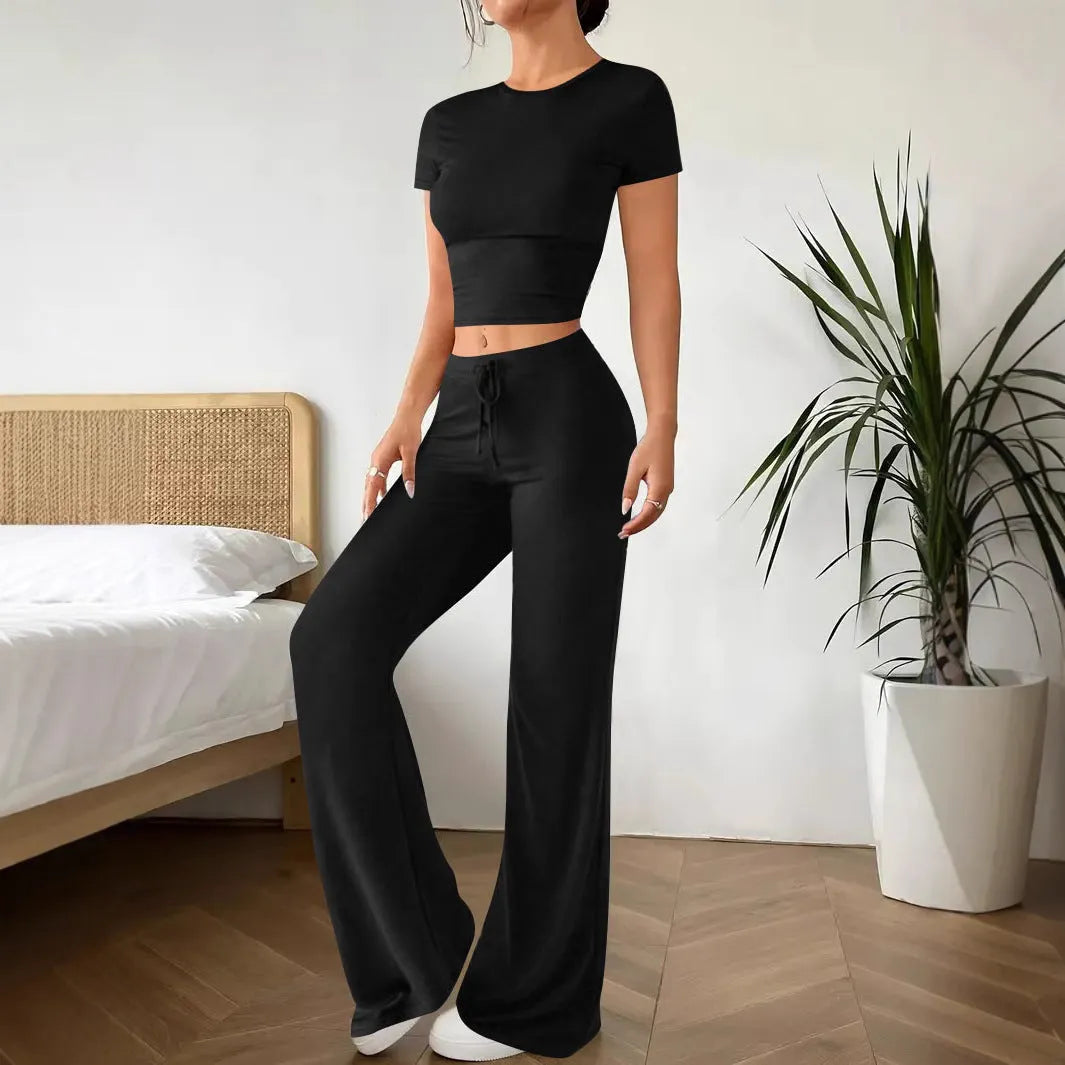 Women's black high waist trousers and short sleeve t-shirt co-ord set laid flat.