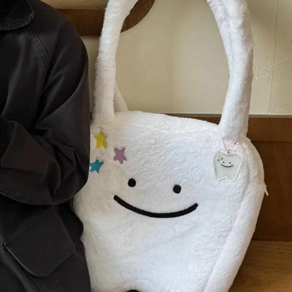 White plush large tooth design shoulder tote bag with zipper closure shown from the front.