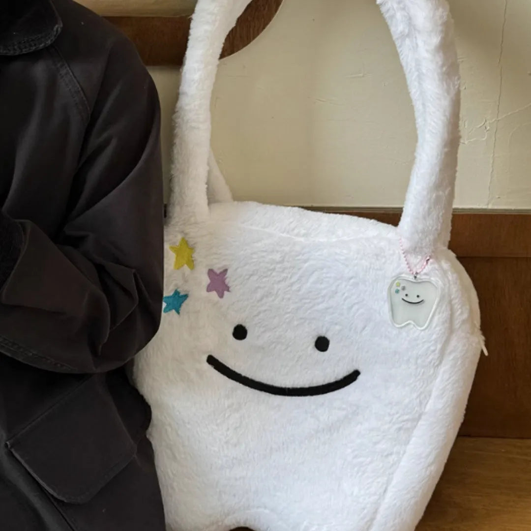 White plush large tooth design shoulder tote bag with zipper closure shown from the front.