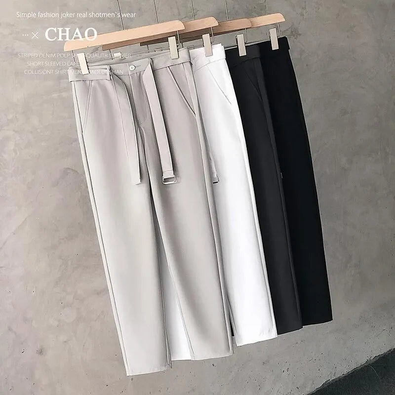 Boy wearing slim straight tapered wool trousers in a grey colour, showing the straight leg opening and belt loops.