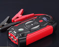 Red 12V portable car jump starter power bank with battery clips on a black background.