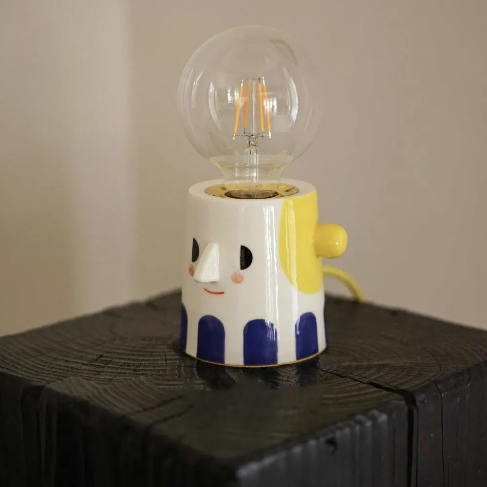 Handmade ceramic bedside lamp with ball headlight design on wooden surface