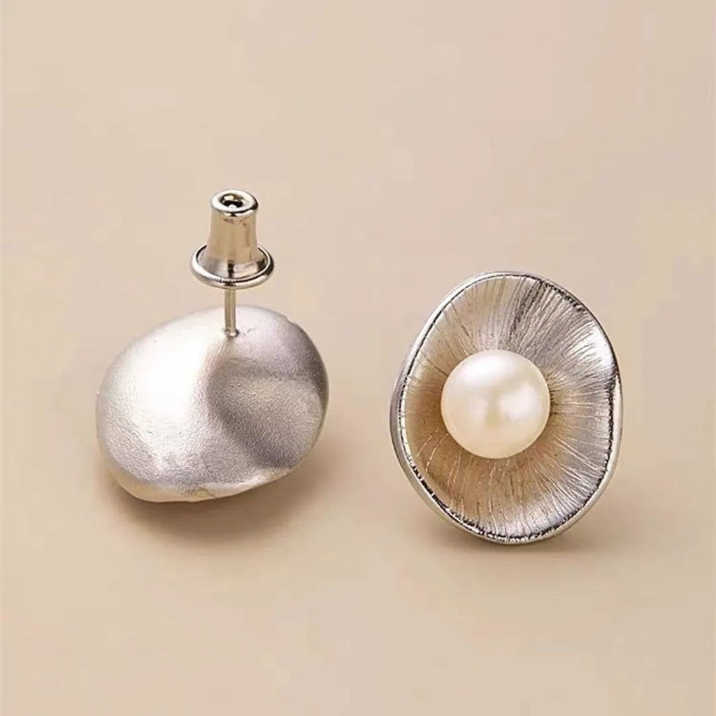 A pair of gold-coloured geometric sterling silver ear studs featuring a central pearl.