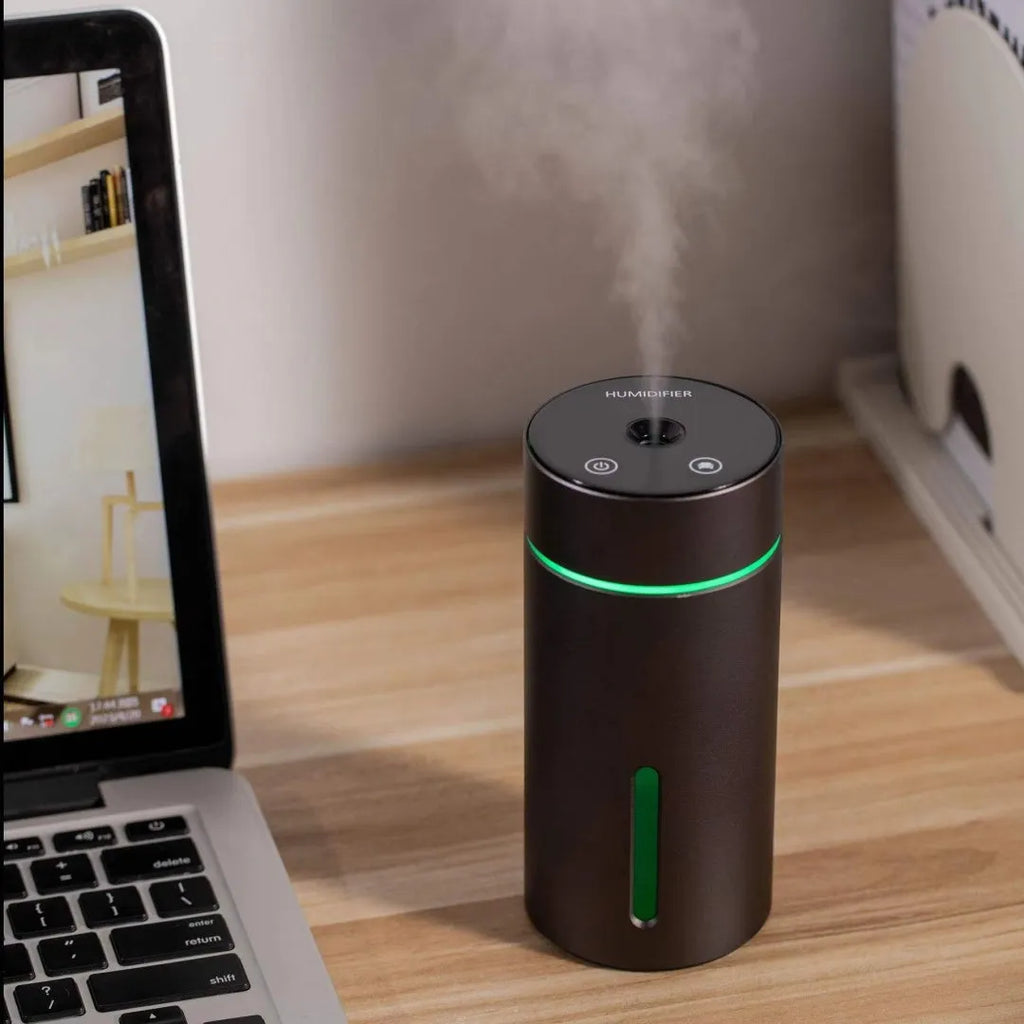 Black aluminium car humidifier diffuser with night light on a desk next to USB cable