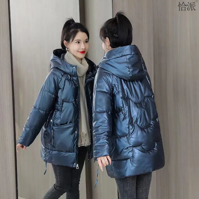 Green loose thick women's winter hooded jacket with long sleeves on a hanger.