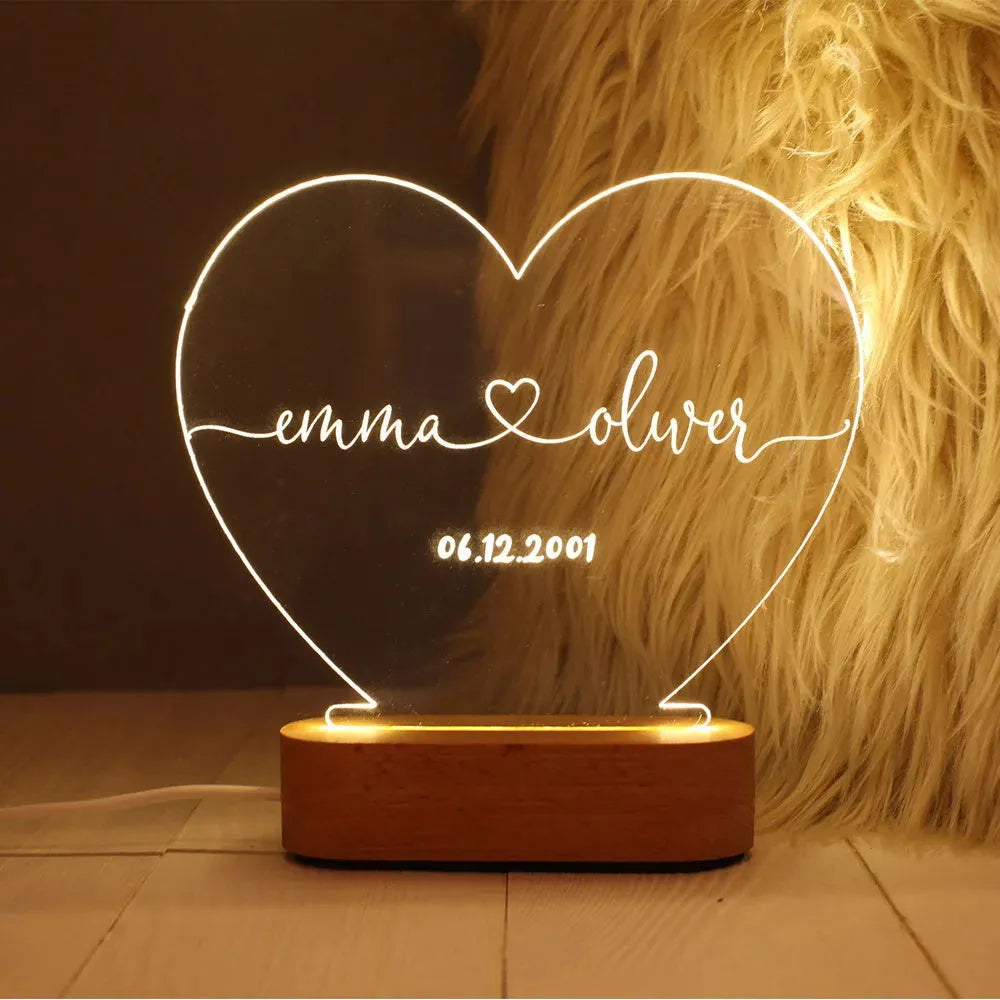 Custom acrylic night light with engraved names illuminated by LED base on bedside table