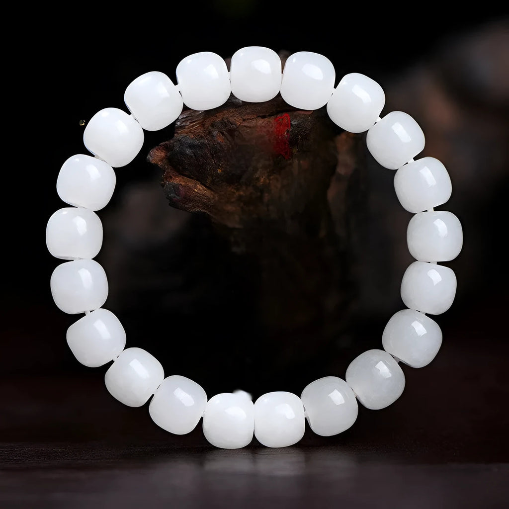 White Hetian jade barrel bead bracelet on a wrist, showing smooth oval beads on a string.