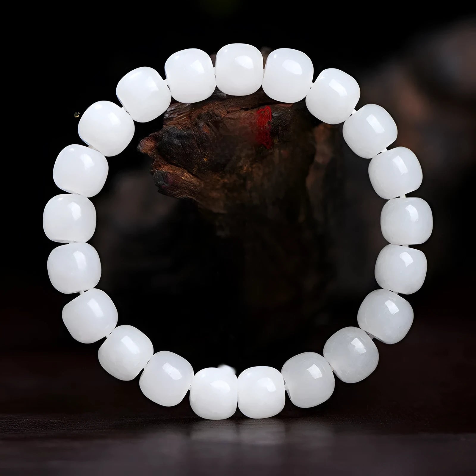White Hetian jade barrel bead bracelet on a wrist, showing smooth oval beads on a string.