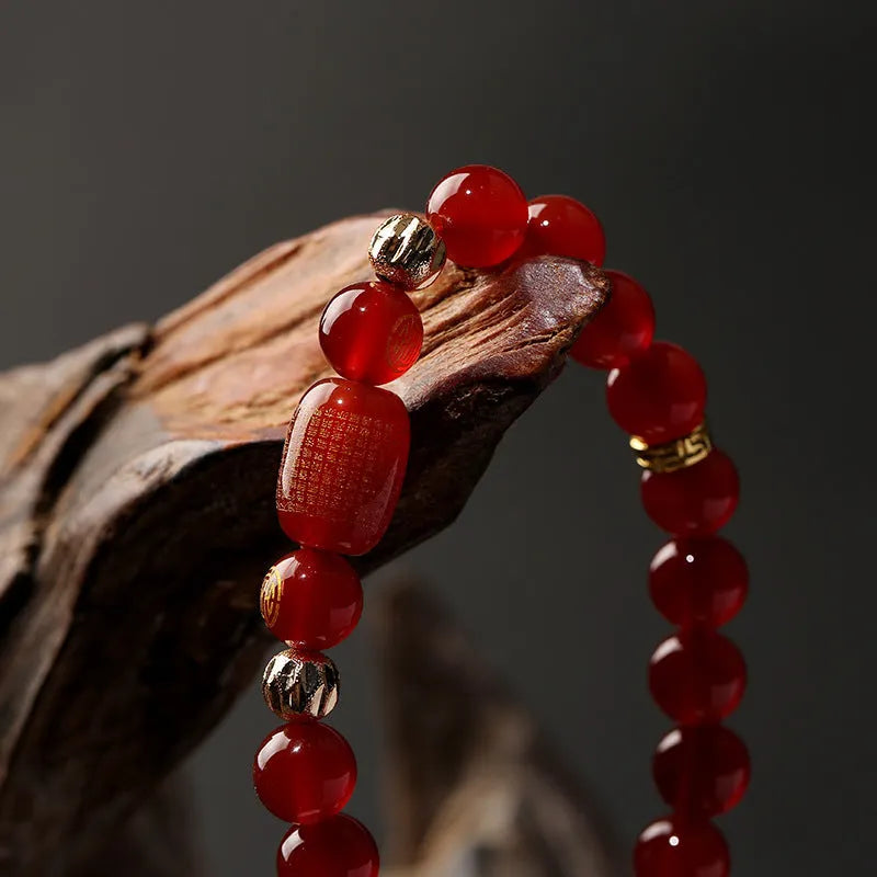 Close-up of a red agate Guanyin bracelet with detailed rosary bead edging on a wrist.