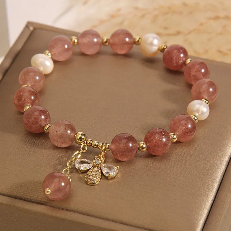 Women's adjustable bracelet with pink strawberry quartz stones, white freshwater pearls, and zircon accents on a wrist.