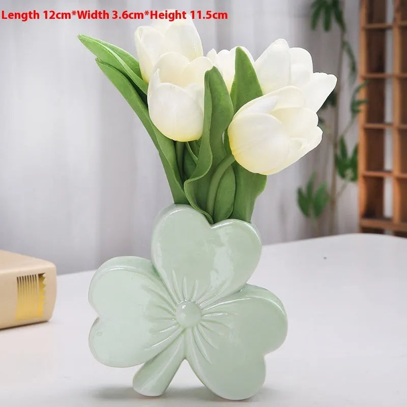 European style white porcelain ceramic vase in four colour options on a desktop.