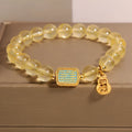 Women's yellow citrine crystal bracelet with sparkling rhinestone details on a white background.