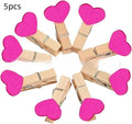 Set of five handmade solid wood heart-shaped clips in red, white, and rose red on a plain surface.