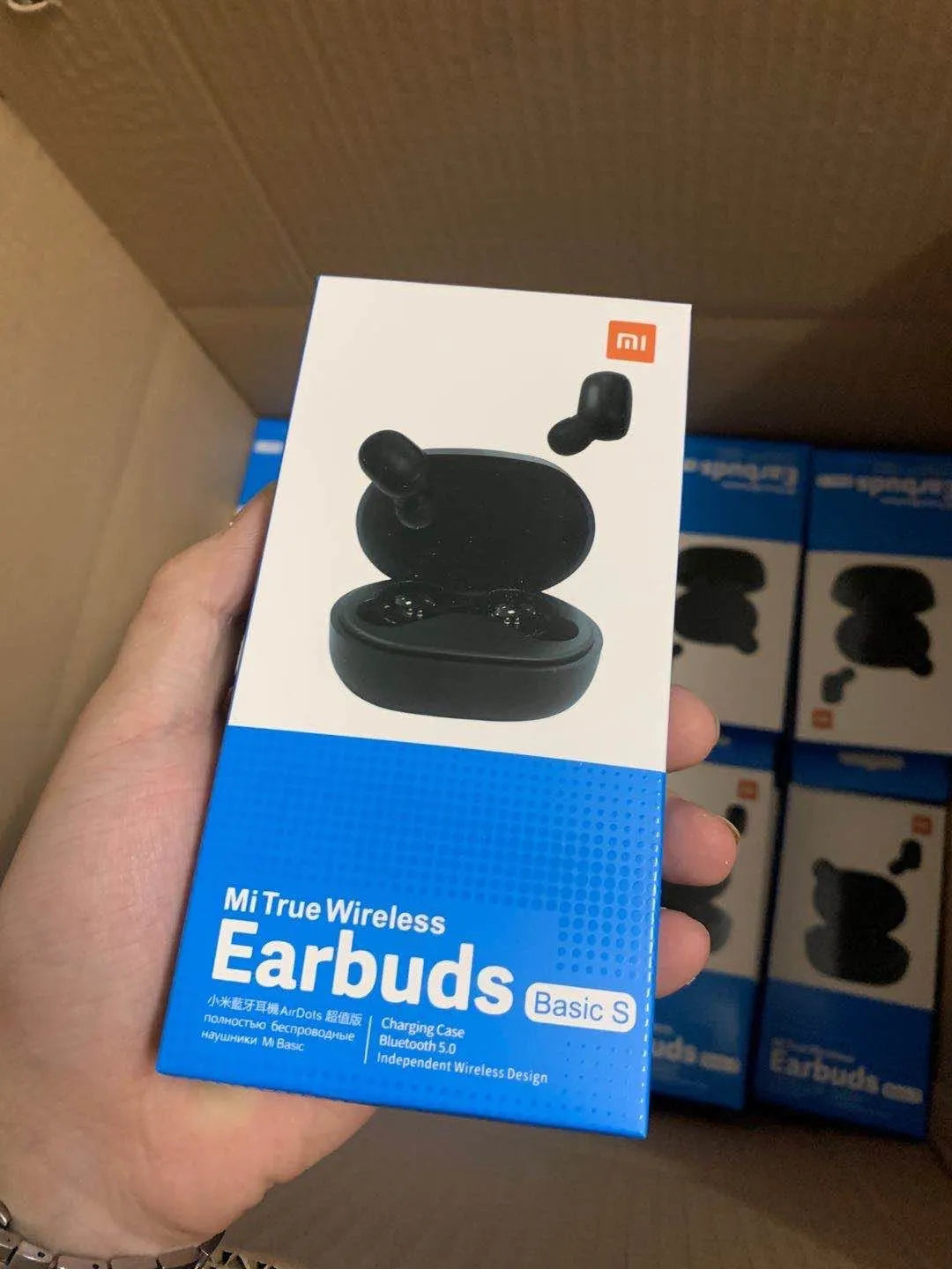 Redmi AirDots black true wireless earbuds next to their compact white charging case.