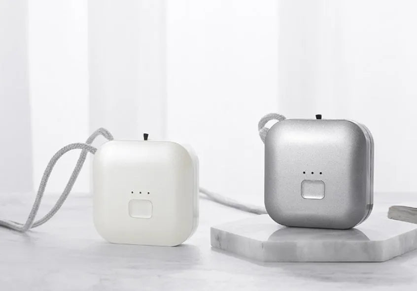 Small pink wearable USB air purifier necklace on a person, showing compact size.