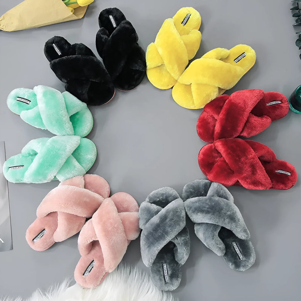 Women's black cross open-toe fur slippers with a patterned non-slip sole on a wooden floor.