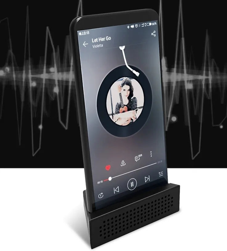 A small black plastic phone amplifier stand holding a smartphone on a desktop.