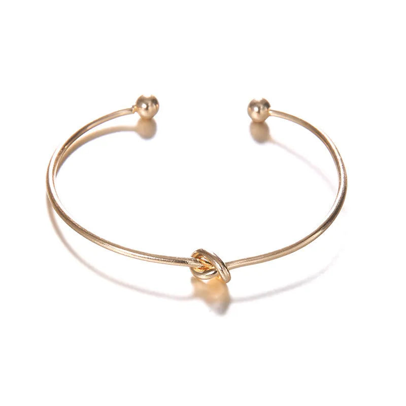 Gold electroplated vintage women's cuff bracelet with arrow and knotted design.