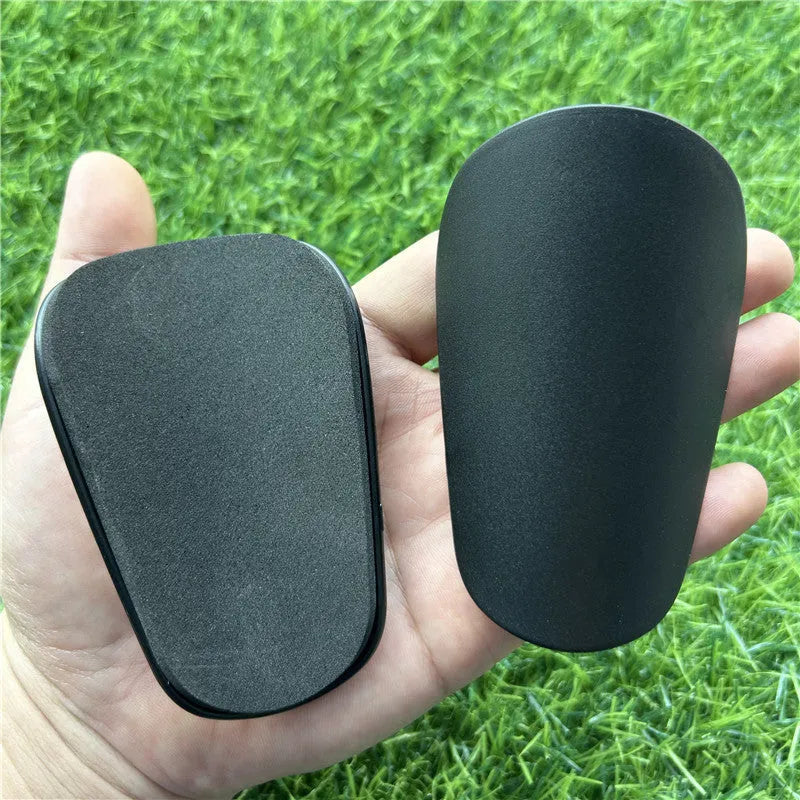 Extra small black and white plastic football shin guards for junior players.