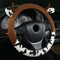 Short plush automotive steering wheel cover in black, showing protective handle detail.