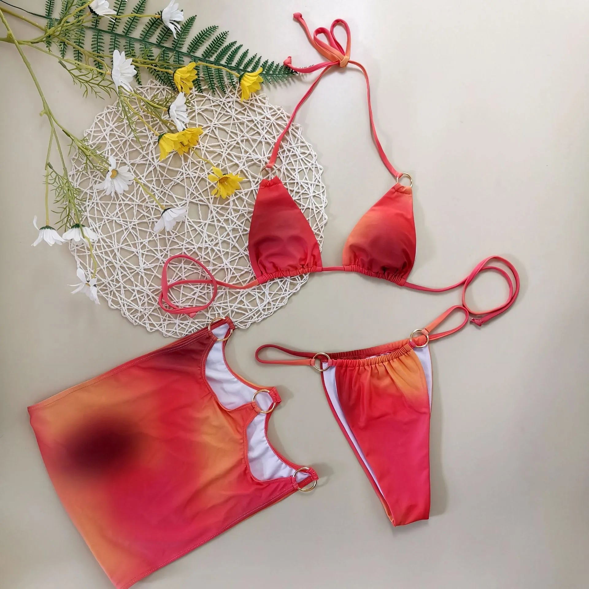 Tie-dye gradient three-piece halter bikini swimsuit set with wrap skirt on a neutral background.