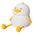 Chubby white silicone rechargeable night light on a wooden desk, showing phone holder function.