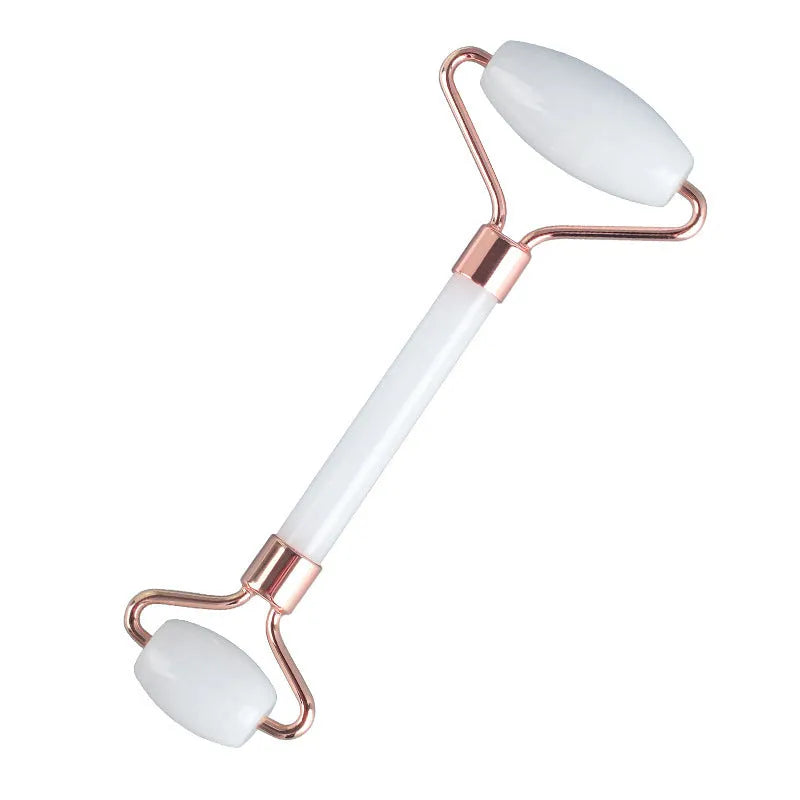 White jade facial roller set with double-headed roller, claw tool, and gua sha board on a wooden table.