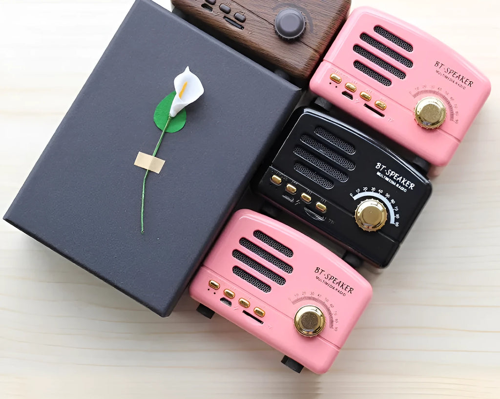 Vintage wood effect Bluetooth speaker in pink, black and wood grain colours showing compact size