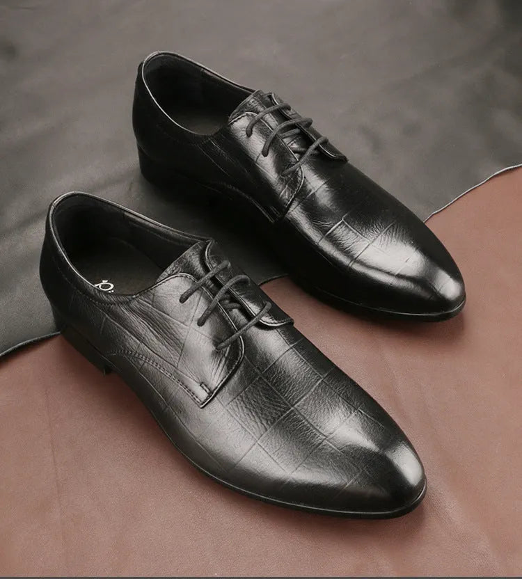 Men's black cow leather derby shoes with a pointed toe and rubber sole on a grey background.