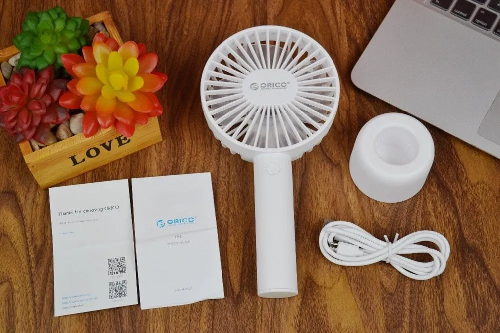 White ORICO FH1 portable USB desktop fan with rechargeable battery on a table.
