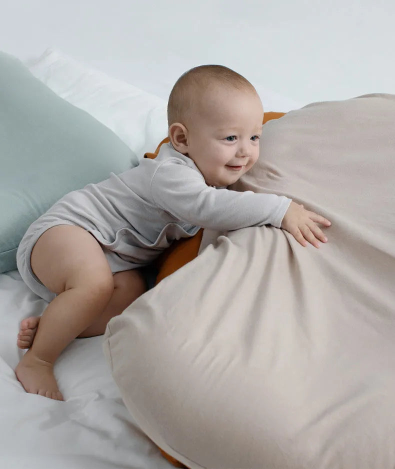 Beige portable cotton baby nest crib for newborns on a neutral background