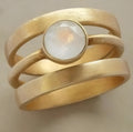 Gold geometric hollow ring with white chalcedony stone on a titanium steel band.