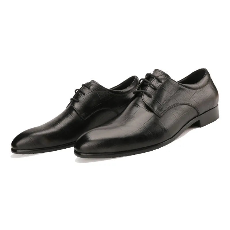 Men's black cow leather derby shoes with a pointed toe and rubber sole on a grey background.