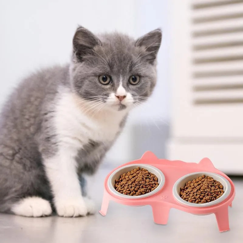 Blue ceramic cat food and water bowls sitting in a white elevated tilted stand with a hook