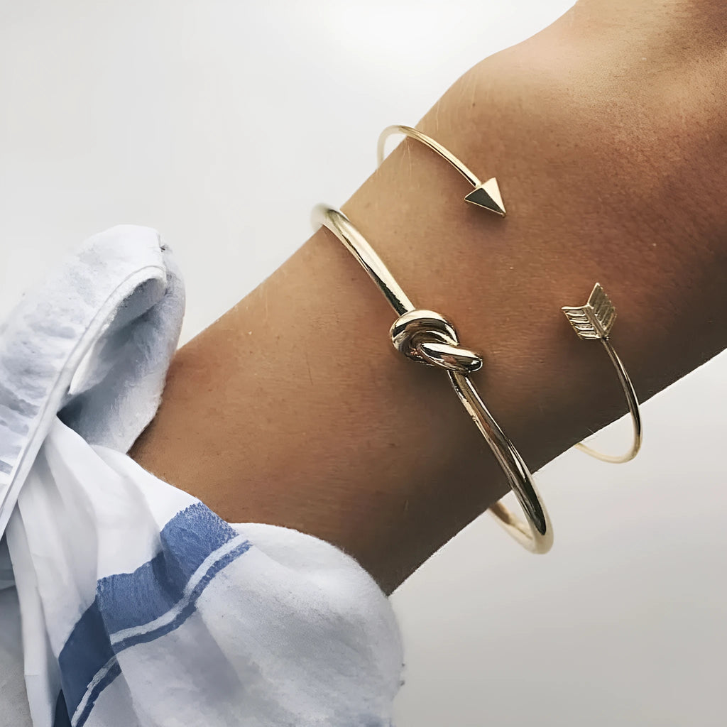 Gold electroplated vintage women's cuff bracelet with arrow and knotted design.