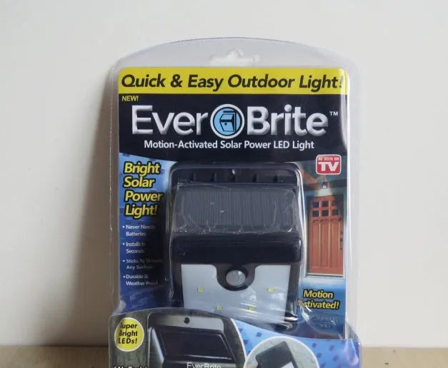 Black rectangular solar-powered outdoor motion sensor light with four LED bulbs.