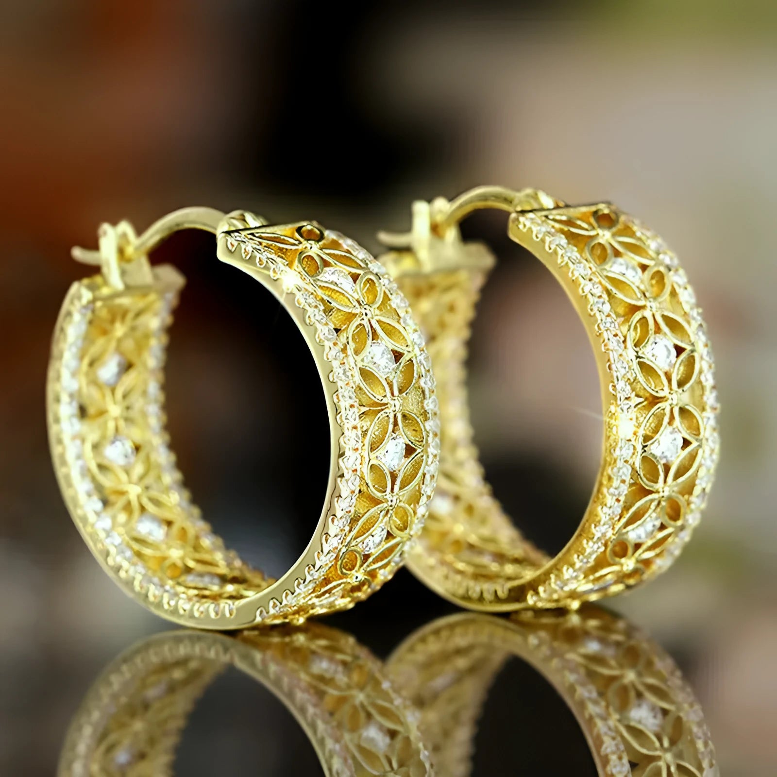 A pair of gold-coloured geometric clip-on earrings with horse, eye, flower and butterfly motifs on a copper base.