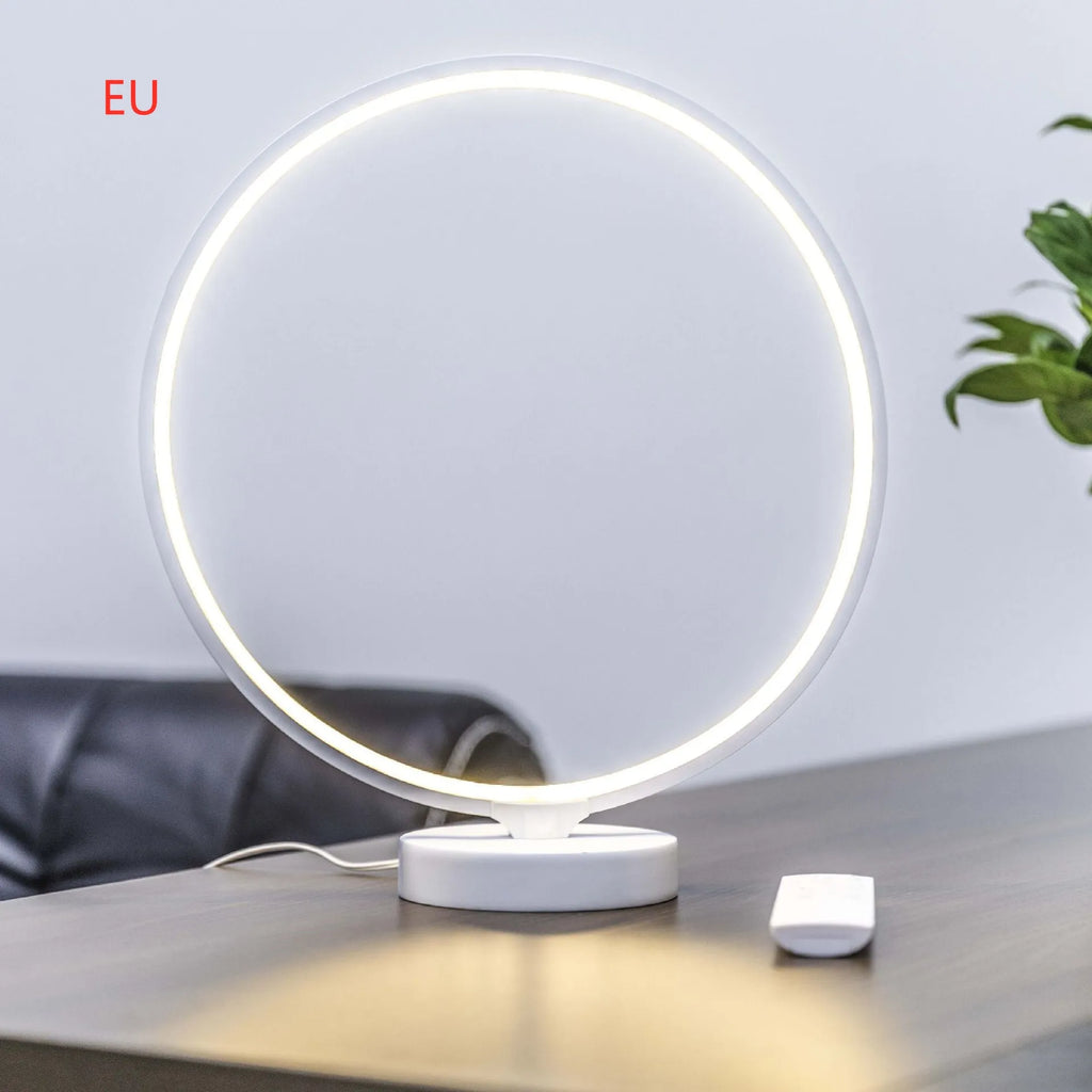 White Full Moon shaped table lamp with remote control on a wooden surface.