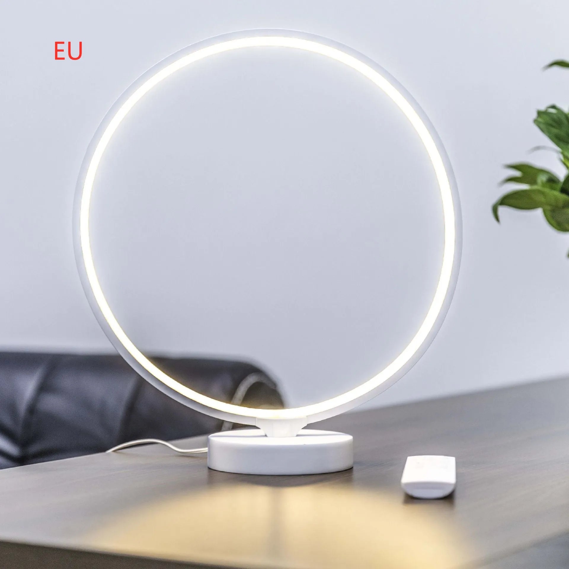 White Full Moon shaped table lamp with remote control on a wooden surface.