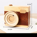 Pine wood camera-shaped music box with rotating mechanism on a wooden base.