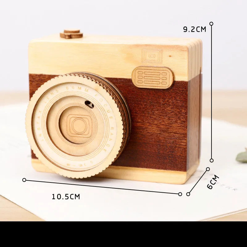 Pine wood camera-shaped music box with rotating mechanism on a wooden base.