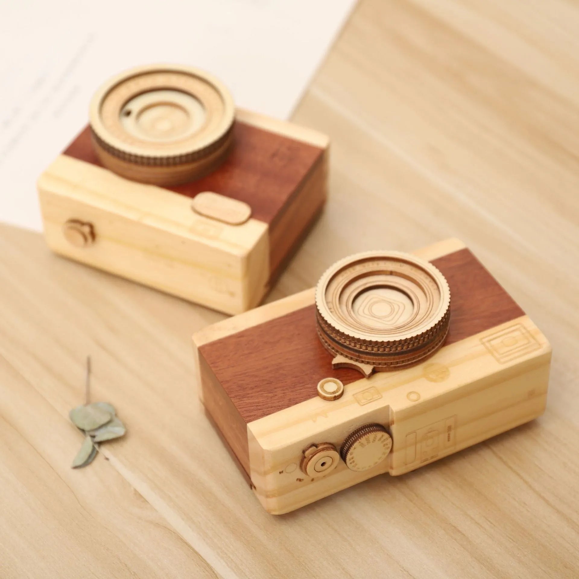 Pine wood camera-shaped music box with rotating mechanism on a wooden base.